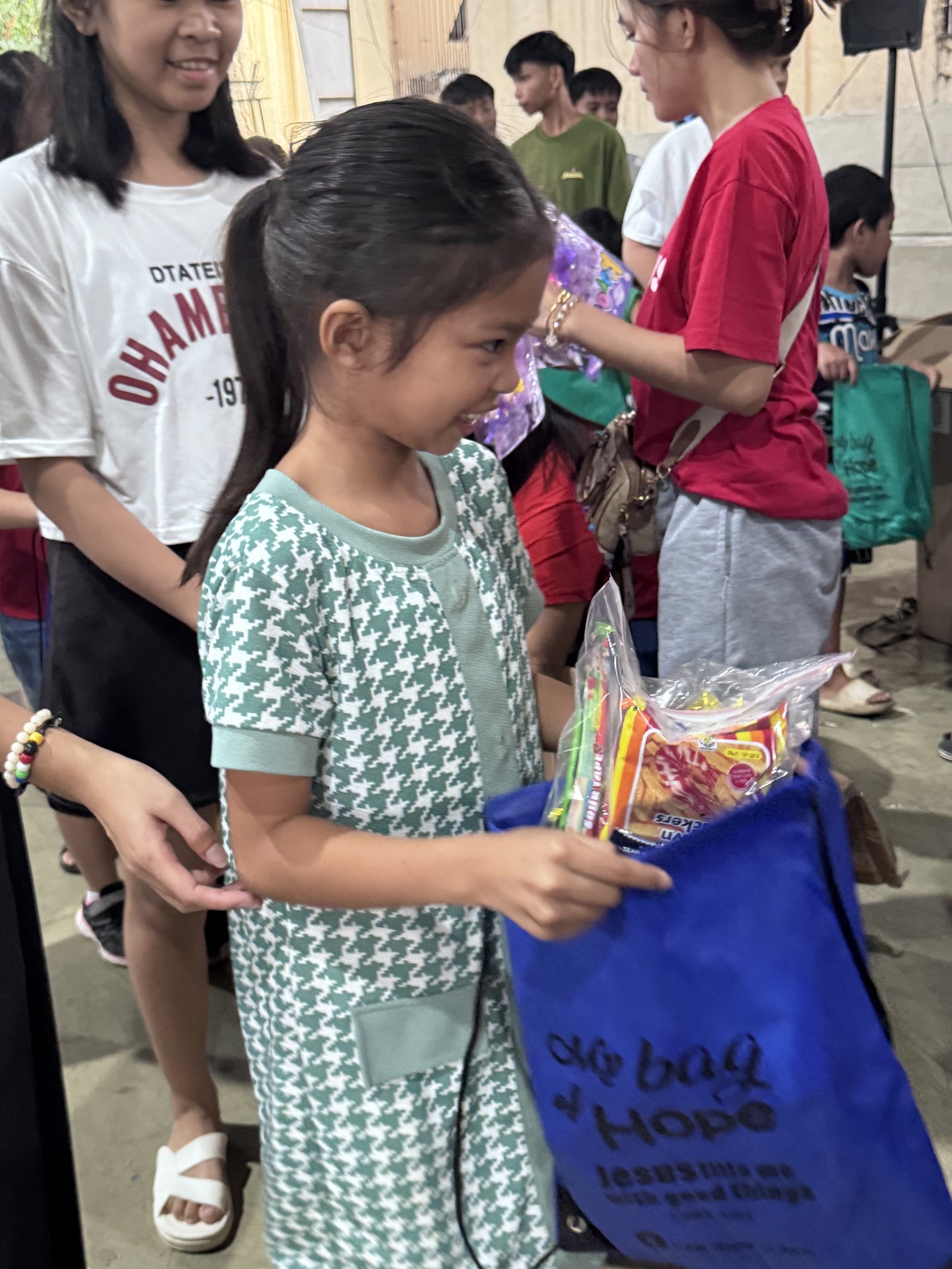 A young girl smiling as she receives her Big Bag of Hope filled with toys and snacks