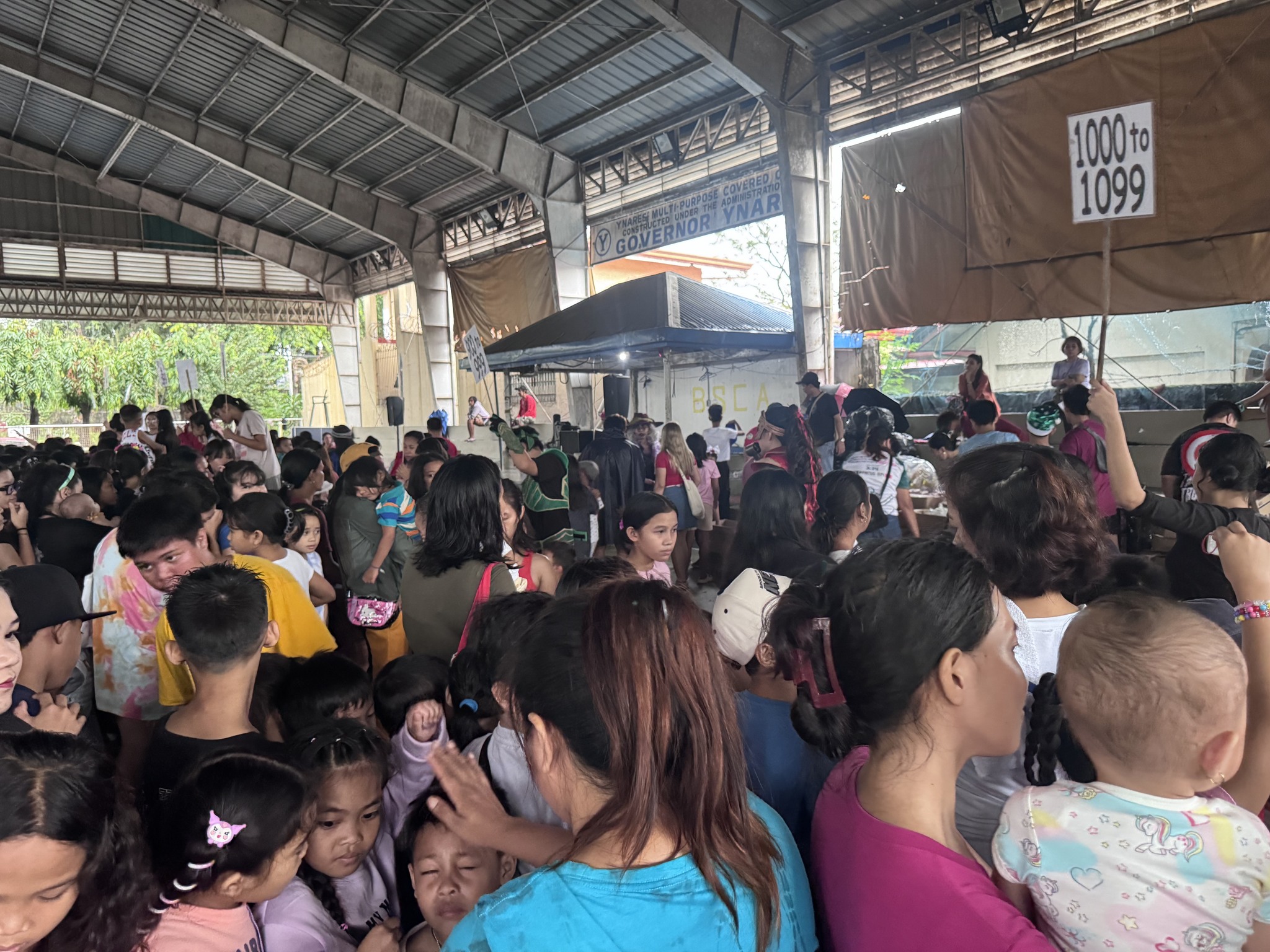 Dense crowd of children and families queueing with number tags during gift distribution
