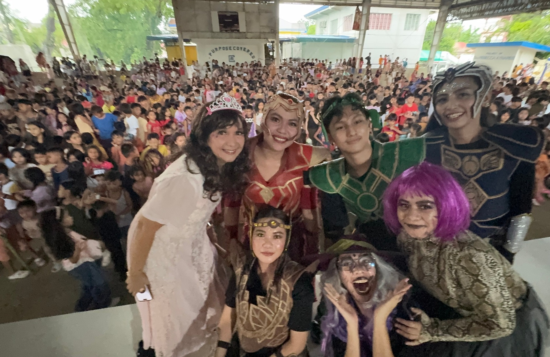 The costumed cast of the skit taking a group selfie with the massive crowd behind them
