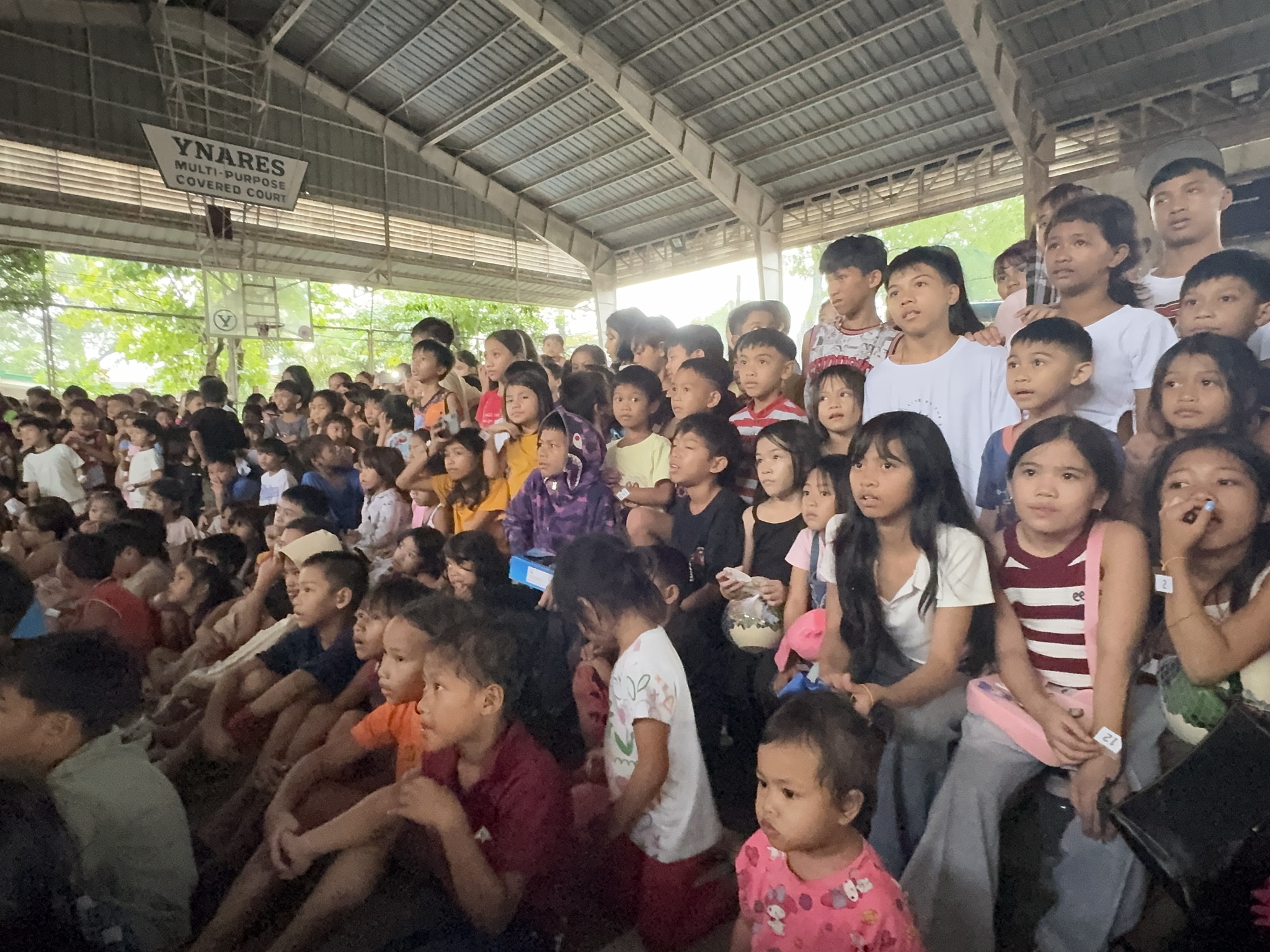 Wide shot of the skit performance with costumed actors on stage and a massive crowd watching