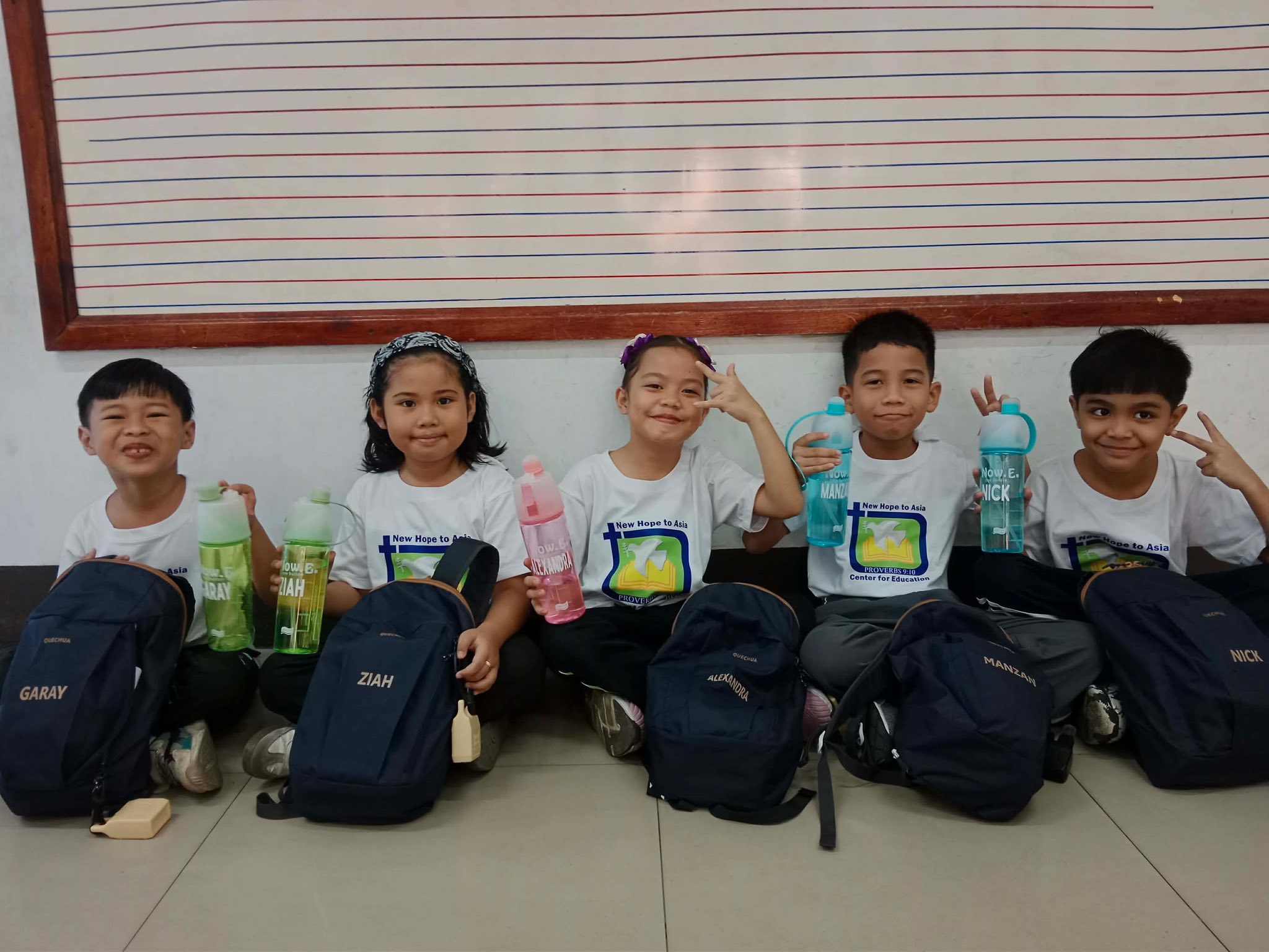 Children showing their new backpacks and tumblers with their names