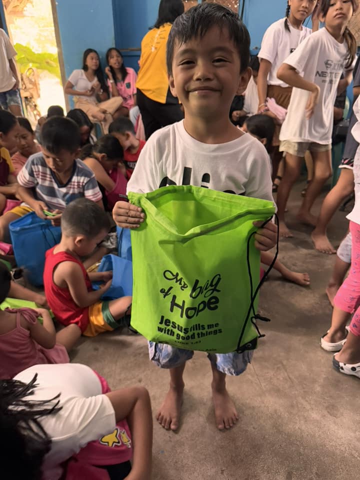 A smiling boy holding his green My Bag of Hope