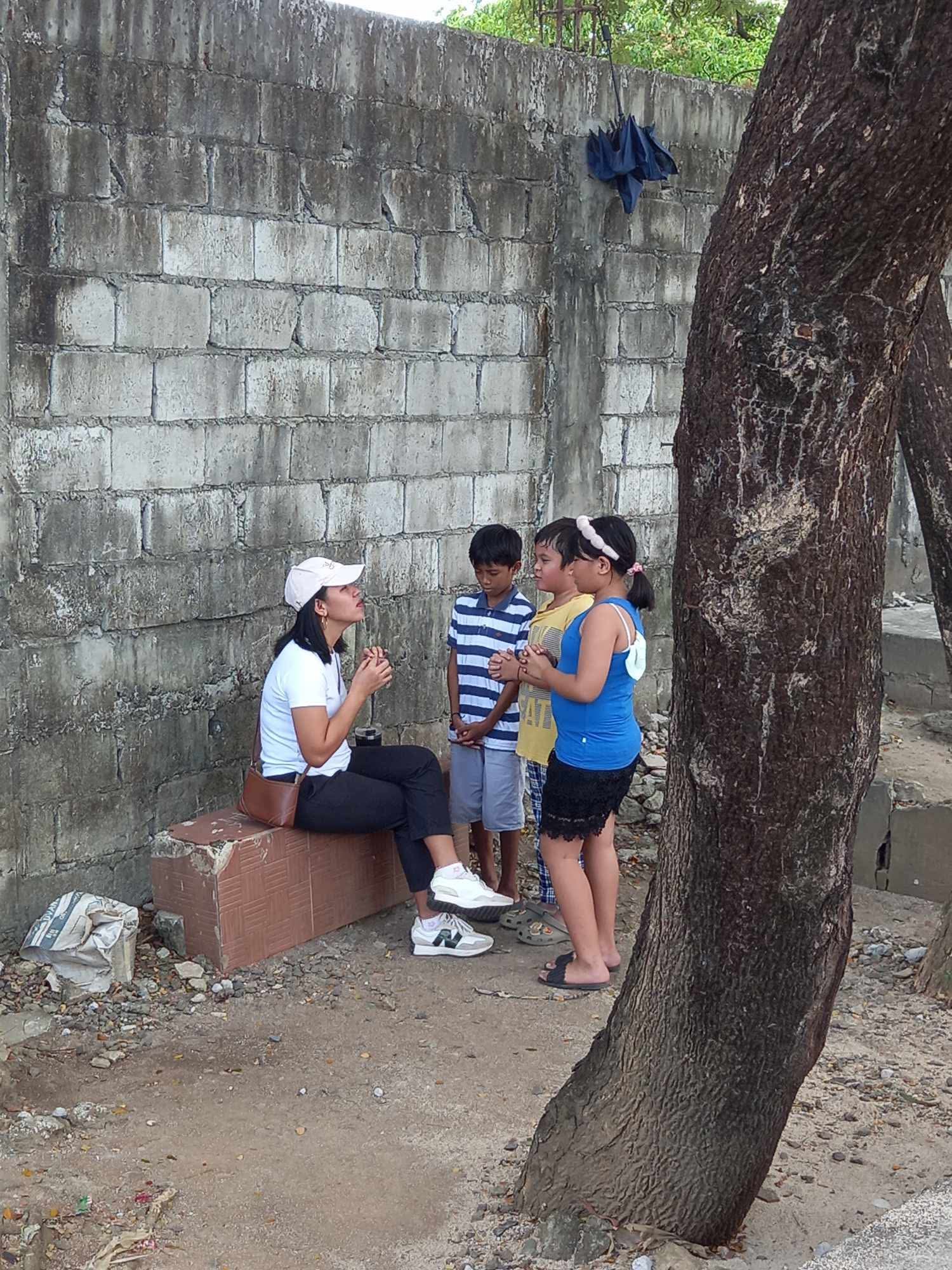 Youth leader praying with children during outreach