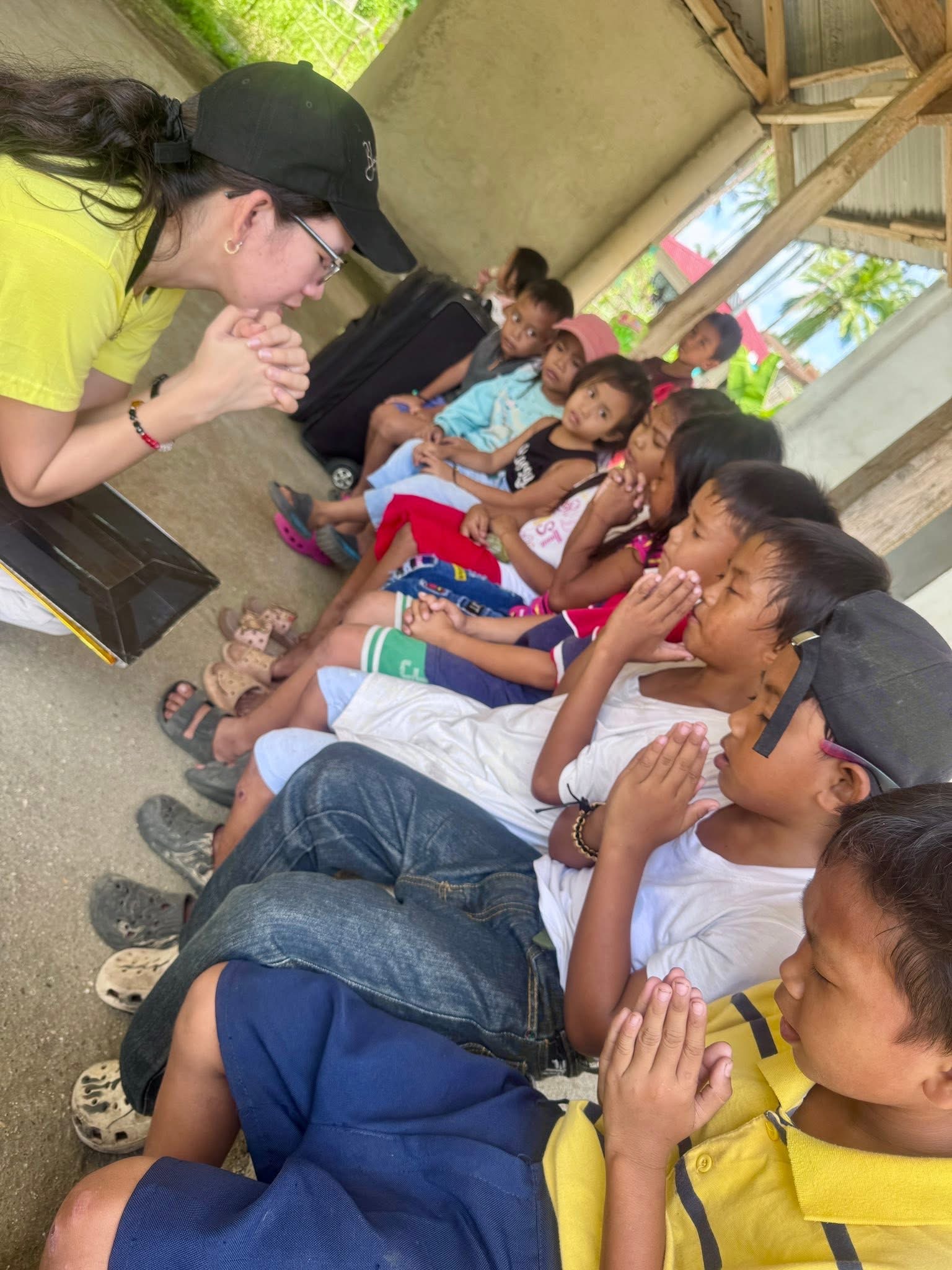 Children bow their heads in prayer alongside a teacher during the Superkids Bible Club in Masbate Province