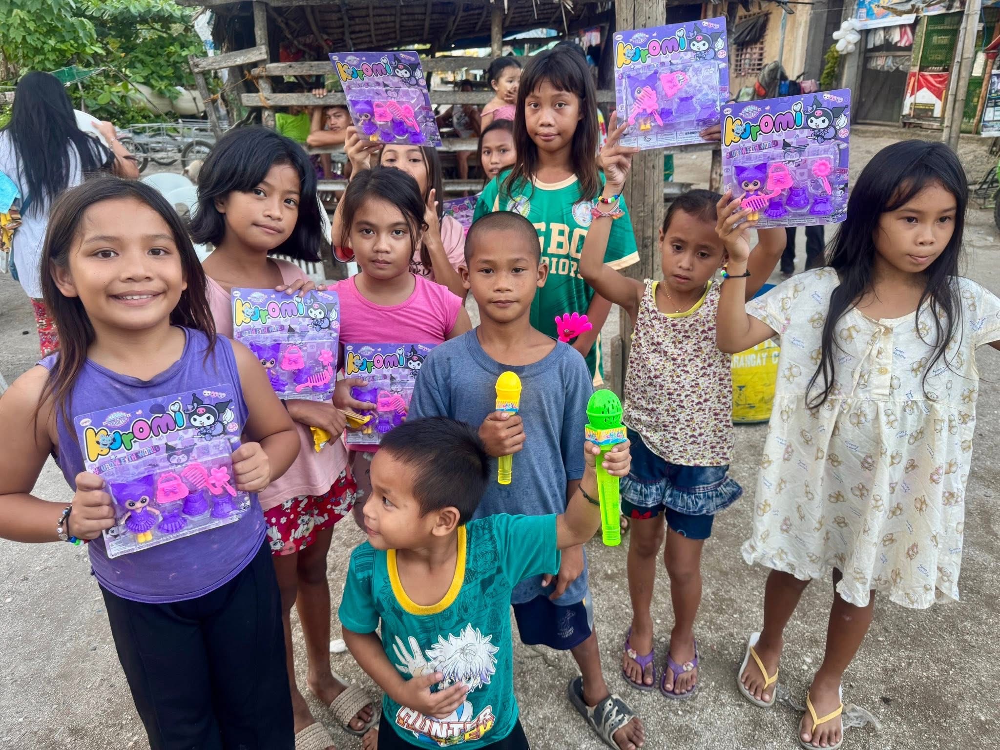 Smiling children hold up toys and gifts received at the Superkids Bible Club in Masbate Province